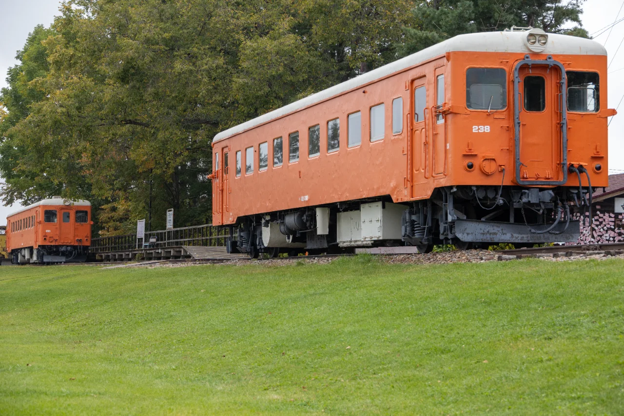 緑の芝生の向こうに見えるオレンジ色の静態保存車両