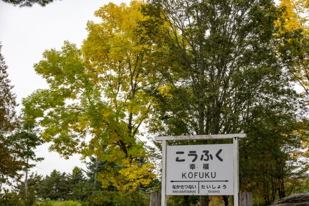 幸福駅の駅名標と紅葉した木々